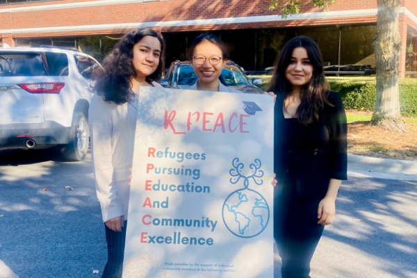 Image of three women in front of an R_Peace sign and what it stands for